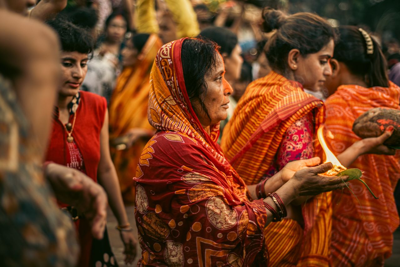 Indian women in colorful sarees engage in a vibrant cultural ceremony.